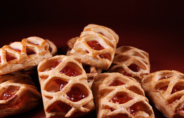 Puff pastry pastry with lingonberry jam on a dark red background. Cookies with lingonberry jam.