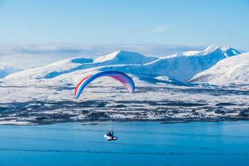 Paraglider flying over the North Norwegian town Tromso in winter