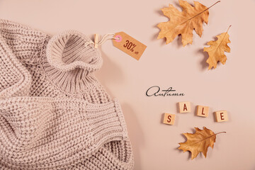 Flat lay composition for seasonal autumn sale with knitted sweater, dry leaves and inscription...