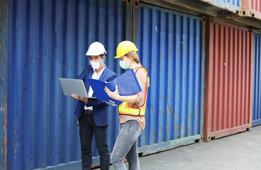 Two Young Engineers standing in the shipping yard tracking the cargo inventory and checking container box for safety.
