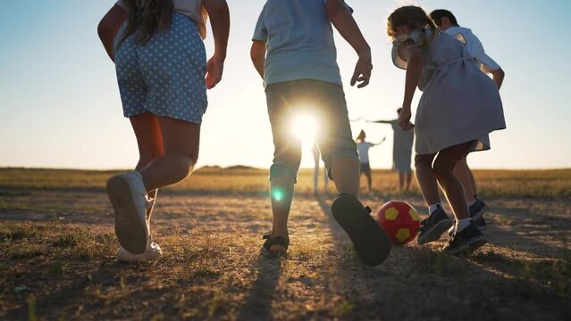 Active family playing football on green grass at sunset.Football fun at sunset active family playing on green grass in park.active children play with ball on grass in park.Happy family summer vacation