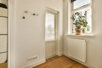 a white room with wood flooring and a window that has shutters on the outside wall to let in natural light