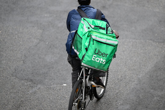 A deliver for Uber Eats or UberEats on his bike or bicycle. Illustration of delivers for home food meal takeaway delivery platforms, in Paris, France on October 19, 2023.
