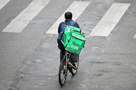 A deliver for Uber Eats or UberEats on his bike or bicycle. Illustration of delivers for home food meal takeaway delivery platforms, in Paris, France on October 19, 2023.