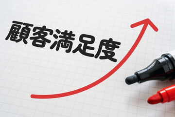 顧客満足度と書かれたノートとマーカー
