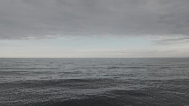 Flying over ocean with grey water. Footage. aerial view flying over water with dramatic clouds