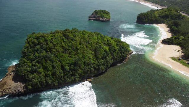 A small island covered with tropical trees is located on Tanjung Penyu Mas Beach