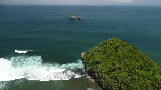 Large rolling waves and small islands at Tanjung Penyu Mas Beach, Java Island, Indonesia