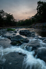 River flowing on rocks sunset background