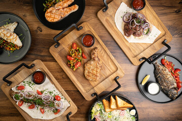 Different grilled bbq dishes on the table in the restaurant. Arabic grilled food dishes kebab