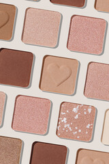 Minimal pattern of eye shadow beige tones swatches, monochrome photo background, eyeshadow with heart imprint, shiny natural shades powder makeup, square shape metal pack, beauty cosmetic texture
