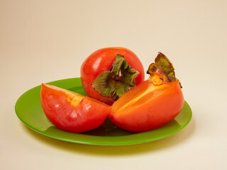 ripe orange persimmon fruit on a green plate