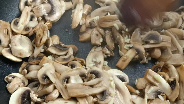 champignons de Paris et ail en cuisson dans une po&ecirc;le
