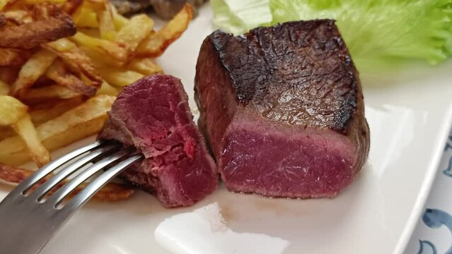 morceau de boeuf grill&eacute; dans une assiette accompagn&eacute; de frites et champignons &agrave; la cr&egrave;me