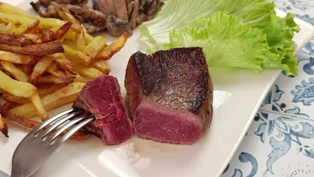 morceau de boeuf grill&eacute; dans une assiette accompagn&eacute; de frites et champignons &agrave; la cr&egrave;me