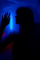 silhouette woman behind blue light poses mysteriously and artistically