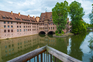 Ancient historical buildings in one of the several water canals of Nuremberg, Bavaria, Germany. Wooden fence in the foreground. Overcasted sky on the background.