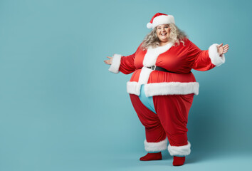 Plus size happy plump girl attractive overweight model on blue background in red clothes in Christmas style, funny clown Santa Claus - obrazy, fototapety, plakaty
