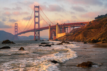 San Francisco: Golden Gate Bridge at sunset seen from Golden Gate Beach with illuminated waves in foreground 