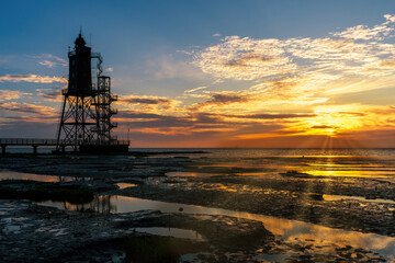 Lighthouse monument Obereversand with wadden sea at sunset 