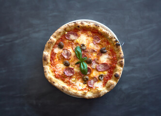 Neapolitan pizza with edges, chilli spices tomatoes and mozzarella on a dark background. Pizza with...