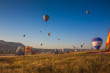 Hot air balloons take off from the ground early in the morning. Hot air balloons flying over bizarre rock landscape in Cappadocia. Beautiful hot air balloons in the morning sky. Goreme. Turkey - obrazy, fototapety, plakaty