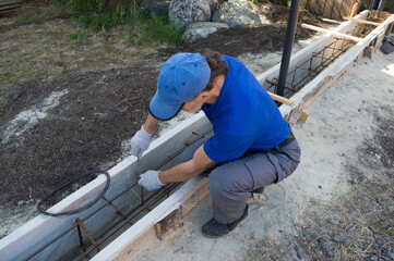 A worker knits rebar for pouring the foundation of the fence.