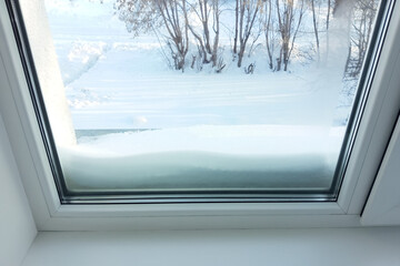 Foggy glass on a plastic window in winter. Snow outside the window. - obrazy, fototapety, plakaty