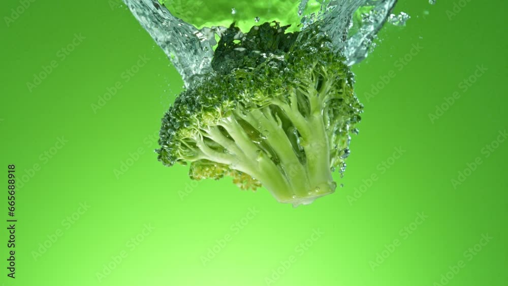 Poster super slow motion of falling fresh broccoli into water on green gradient background. filmed on high 