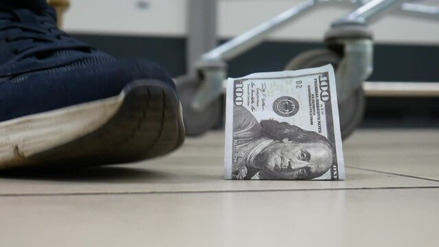 A lost hundred dollar bill lying on the floor and a man with a shopping trolley finds it