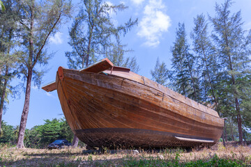 An ancient tugboat built of wood on the beach..A large wooden boat is displayed on the beach with a...