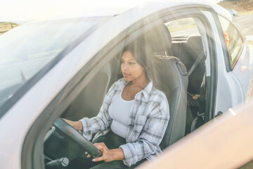 Portrait of a woman sitting in a car and  holding on to the steering wheel