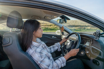 Portrait of a woman sitting in a car and  holding on to the steering wheel