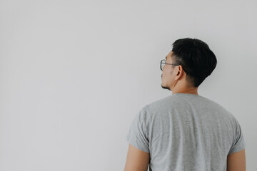 Back side, rear view of Asian man wear grey, haircut done. standing and thinking idea something, choosing and looking at empty space, isolated on white background wall.