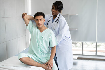 African American Doctor or Physiotherapist working examining treating of caucasian patient,...