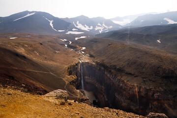 Beautiful landscape of Kamchatka Peninsula: view of Dangerous Canyon , picturesque waterfall on the river Vulkannaya under the active Mutnovsky Volcano.