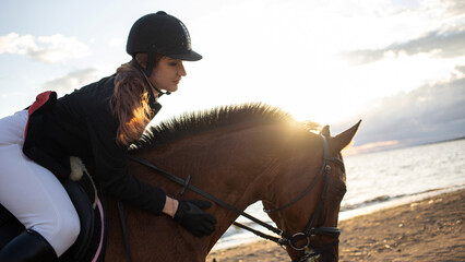 Horsewoman in equestrian sports gear, riding a horse, on the beach, portrait on the background of...