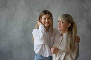 Happy family, women together. Mom and adult daughter smile at each other, studio photo in casual style