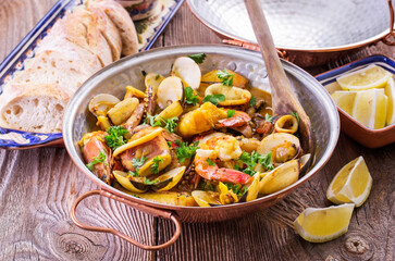 Traditional Portuguese seafood cataplana with king prawns, vongole clam and squid in white wine sauce served as close-up in a design cataplana pot