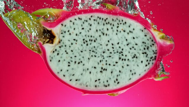 Super slow motion of falling fresh pitahaya into water on red gradient background. Filmed on high speed cinema camera, 1000 fps.