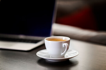 cup of coffee and laptop on wooden table
