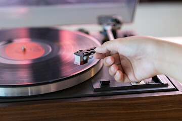 Close up woman hand put the needle on a record, playing vinyl disc at the party. Female dropping the needle on a long playing vinyl record. Music on vinyl discs. - obrazy, fototapety, plakaty