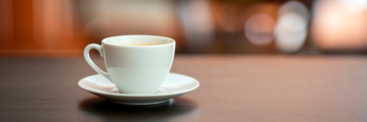 White cup of coffee on wooden table in coffee shop.