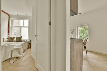 a bedroom with white walls and wood flooring in the fore - image is taken from another room,...