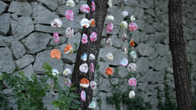 Decorated artwork hanging on a mobile near a stone wall outdoors