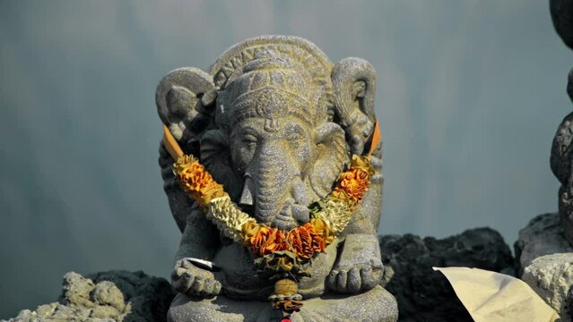 Ancient stone statue of Ganesha stands on a top of volcano Bromo