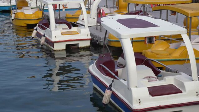 Numerous pedal boats for hire sit idle on river water waiting on people