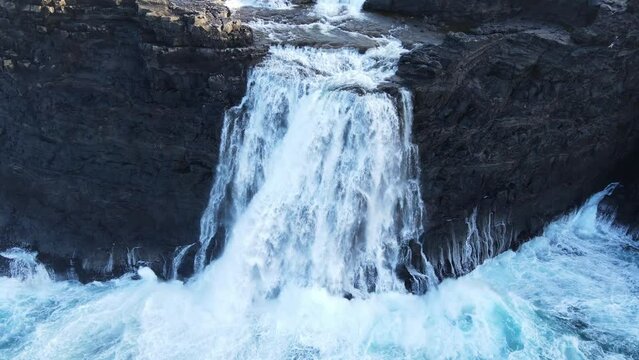 Close drone footage of the B&oslash;sdalafossur Waterfall near the Leitisvatn Lake, aka the Floating Lake, on the Vagar island in the Faroe Islands.
