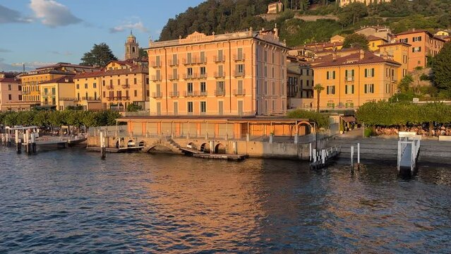 cinematic video of a large and yellow apartment building in a small italian town on lake como called bellagio during the sunset hours on the weekend.