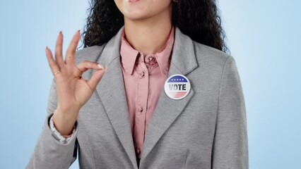 Woman in studio with pointing to vote, badge showing choice, okay and government party support. Politics, voting register or decision, politician with pin for campaign and election on blue background